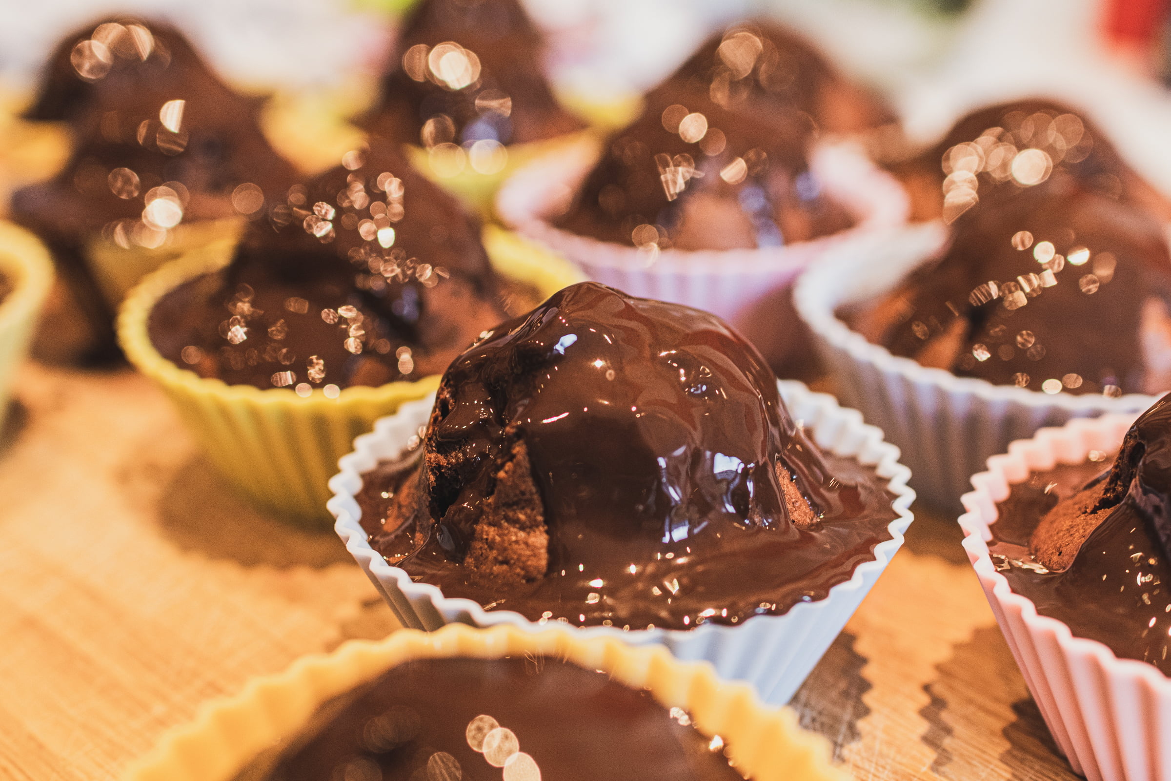 Some muffins glazed with chocolate that's still fluid and sparkling.