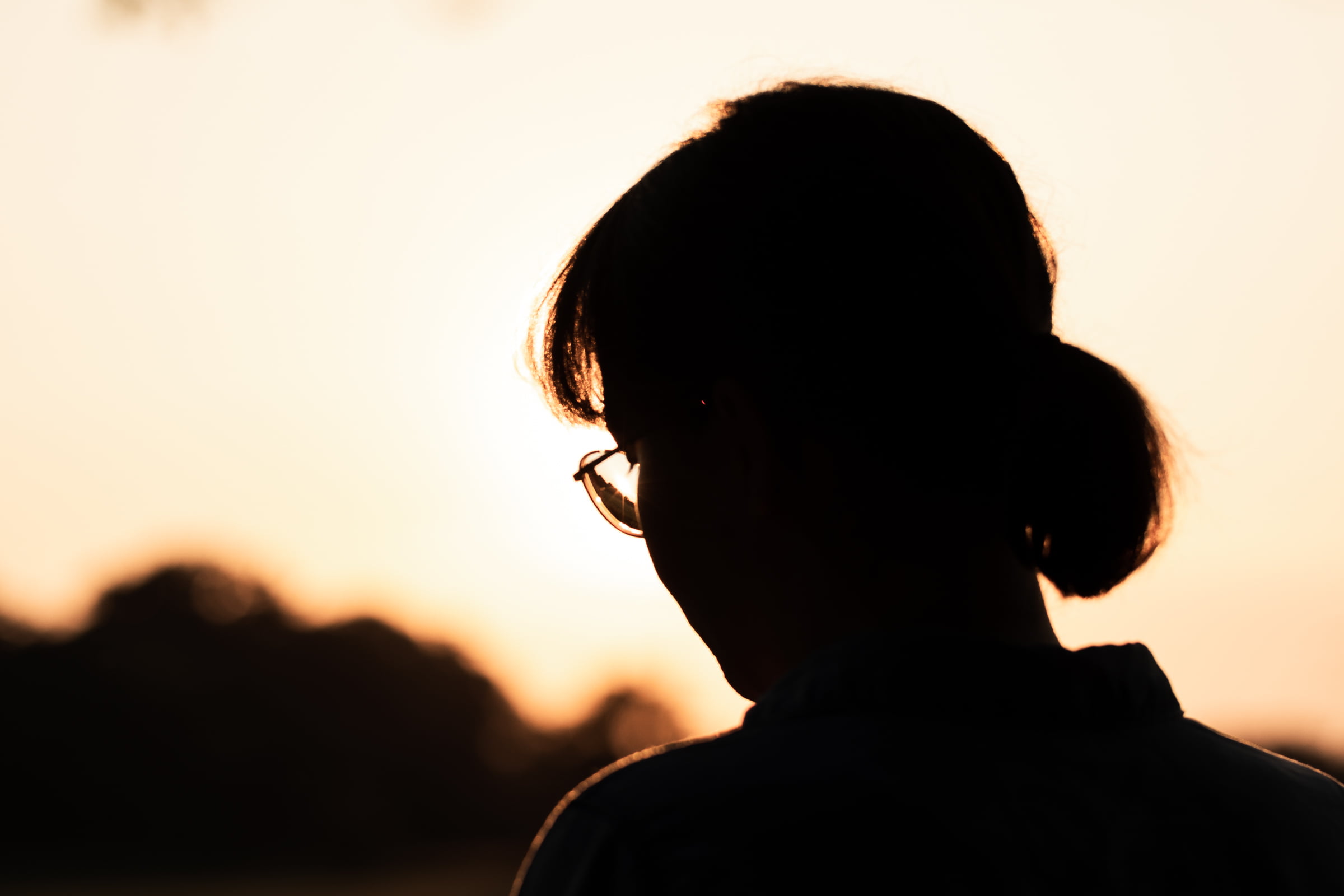 Silhouette of a woman's head against an orange sunset.